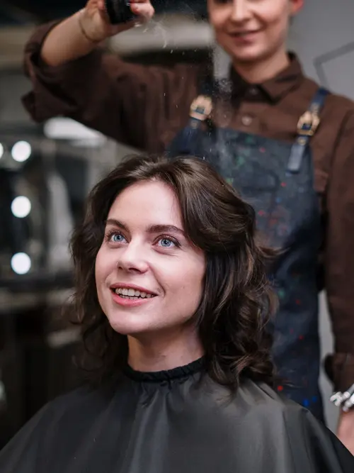 Client smiling while her hair is finished in a salon chair
