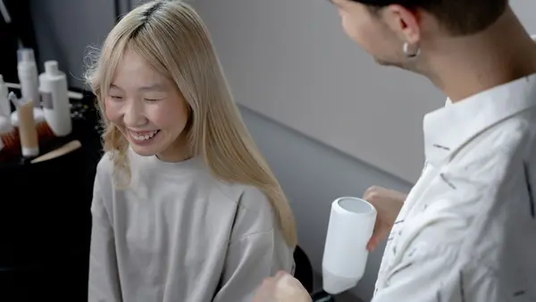 Client smiling while her hair is blow dried and styled in a salon