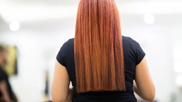 Long copper red hair coloured and straightened, viewed from behind in a salon