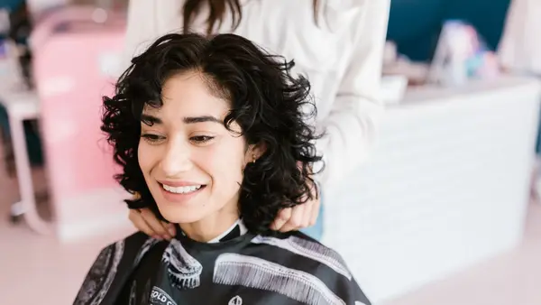 Client smiling in the chair after a cut and blow dry at a hairdressing salon