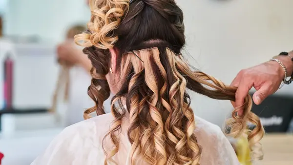 Stylist setting long curls into an occasion hairstyle at a salon