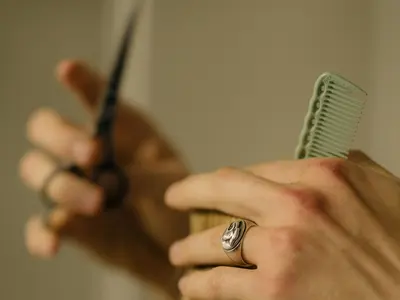Hairdresser cutting a section of hair with scissors and a comb