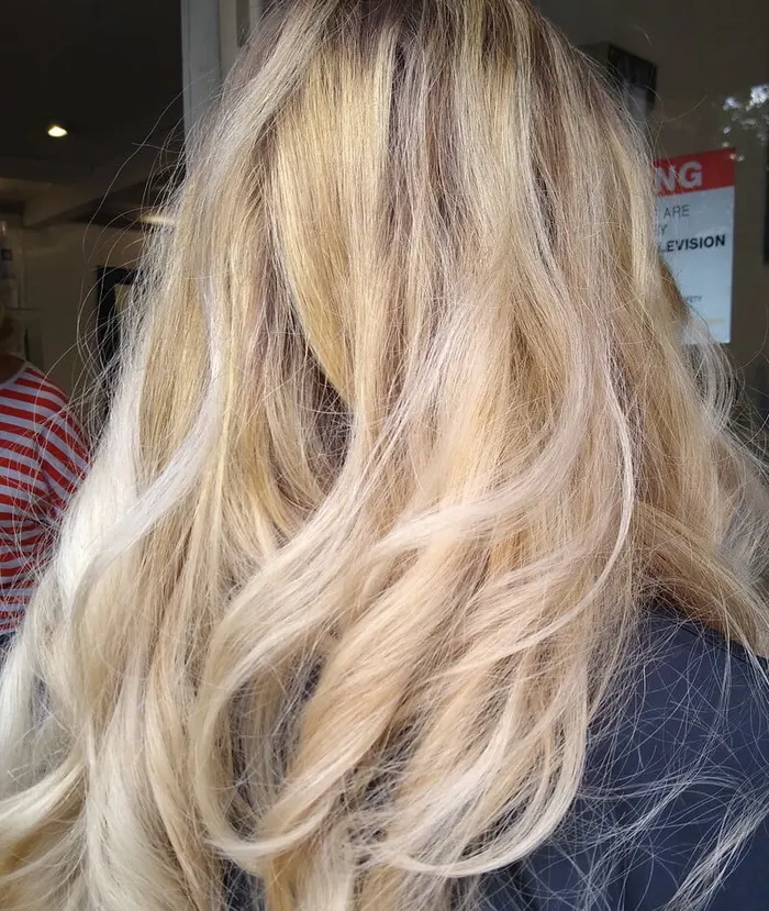 Long blonde balayage with soft waves by Harvey's Hairdressers, Luton